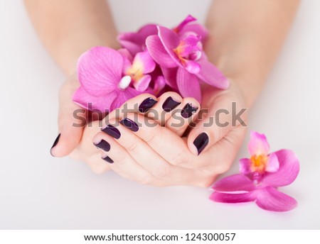 Woman with beautifully manicured purple nails holding a handful of pink flower petals