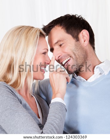 Laughing attractive woman touching her husband affectionately on the nose with the tip of her finger