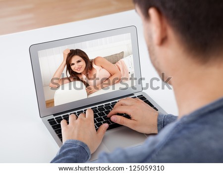 Over The Shoulder View Of A Man Having A Videochat With His Attractive Young Girlfriend Whose Picture Is Shown On The Screen