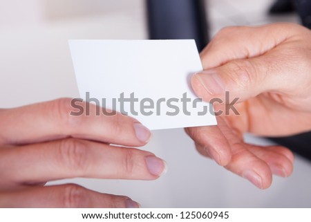 Closeup cropped view image of a man handing a woman a blank white business card for your advertising or contact details