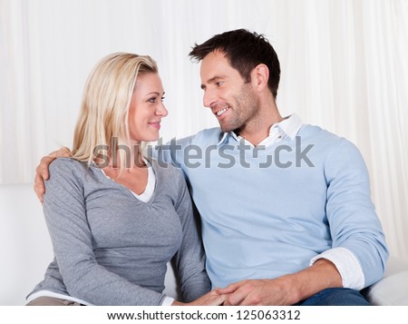 Playful lovely couple sitting together at home