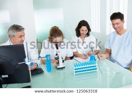 Paramedical or technical staff grouped together looking at a computer in a laboratory