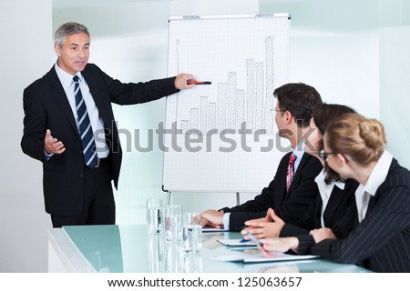 A senior business executive delivering a presentation to his colleagues during a meeting or in-house business training