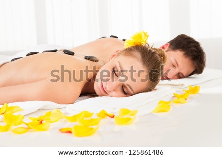 Couple having a hot stone massage treatment in a spa relaxing as the heat from the stones relaxes their muscles