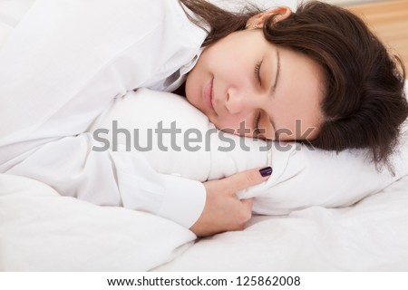 Attractive woman sleeping peacefully with her hand tucked under the pillow as she enjoys sweet dreams