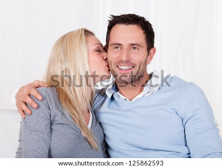 Romantic young couple expressing their love by rubbing noses as they sit close together on a sofa