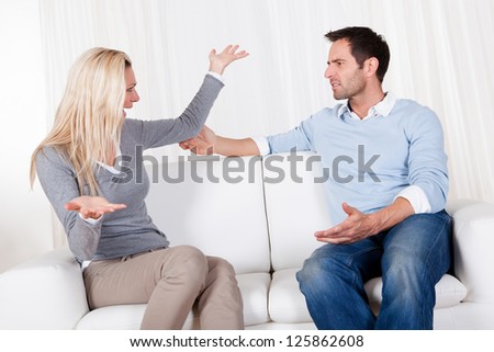 Couple who have fallen out over a disagreement sitting on a sofa