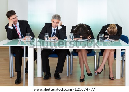 Bored panel of professional judges or corporate interviewers lounging around on a table napping as they wait for something to happen
