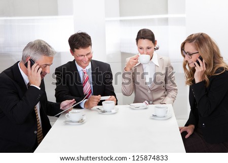 Business executives sitting around a table enjoying a relaxing cup of coffee together during a break