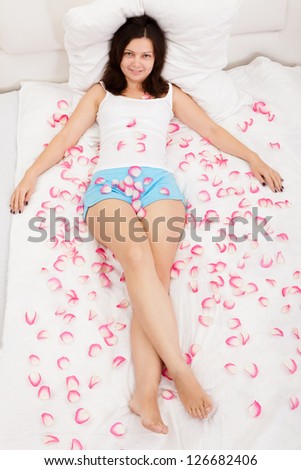 Young brunette woman relaxing on a bed with white bed covers