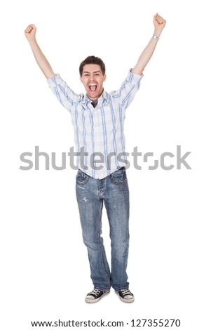 Casual handsome young man in jeans shouting for joy raising his hands above his head