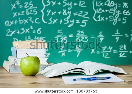 School textbooks on a desk in front of blackboard