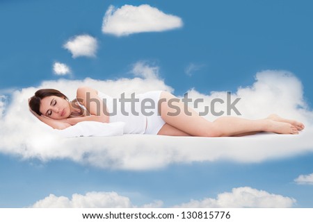 Beautiful Young Woman Sleeping On Clouds In Sky