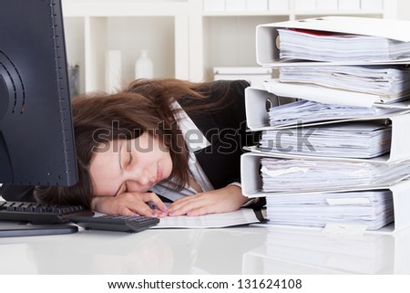 Stressed Businesswoman Sleeping In Office With Stack Of Folders