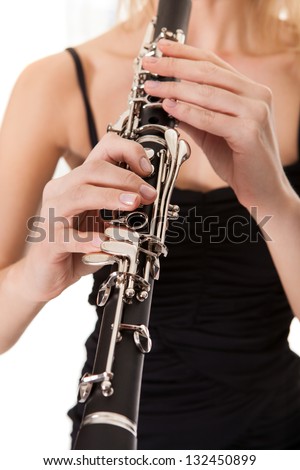 Beautiful young woman playing clarinet over black background