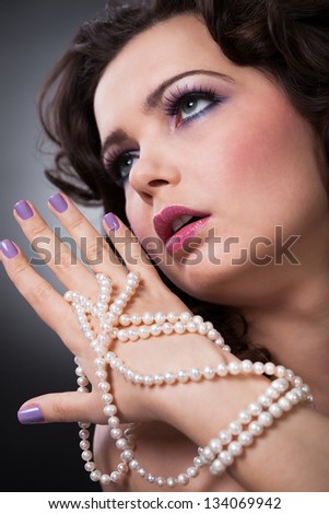 Portrait Of Beautiful Young Woman Holding Pearl Necklace
