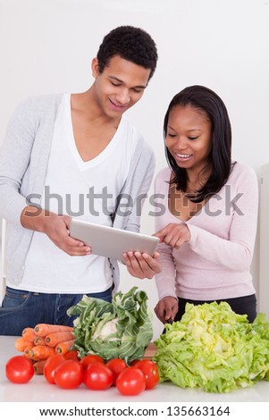 Portrait Of African Couple With Vegetables And Digital Tablet In Kitchen