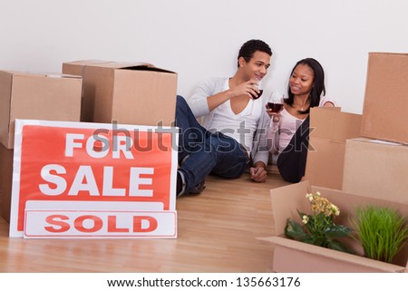 Portrait Couple Sitting Among Moving Boxes Making Celebration In House
