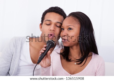 Portrait Of Young Couple Singing With Microphone