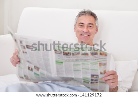 Portrait Of Happy Mature Man Holding Newspaper