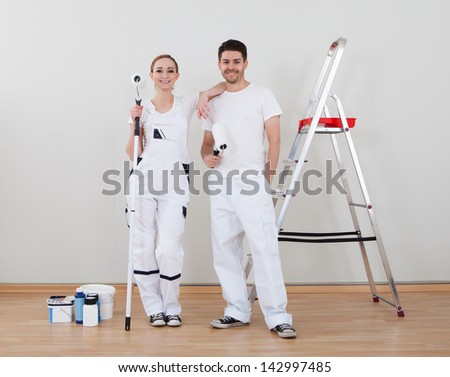 Portrait Of Young Happy Couple Holding Paint Roller