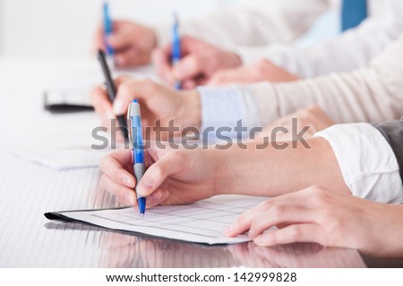 Business People Sitting In A Row And Writing Notes In Office