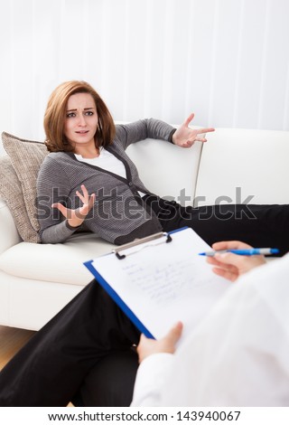 Business woman reclining comfortably on a couch talking to his psychiatrist explaining something