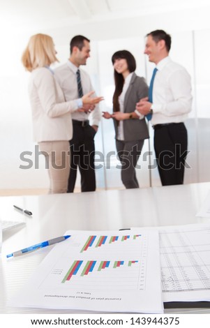 Business People In Conversation And Graph Chart On Table