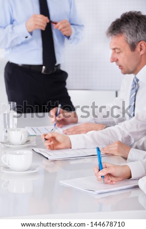 Portrait Of Businesspeople Writing Notes In Business Meeting