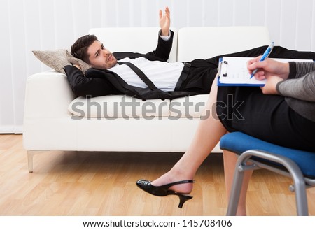 Business man reclining comfortably on a couch talking to his psychiatrist explaining something