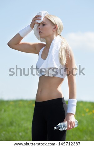 Tired Woman With Water Bottle And Wiping Face With Towel After Exercise