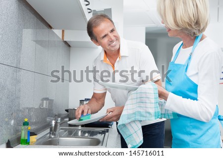 Mature Man Helping His Wife In Household Work
