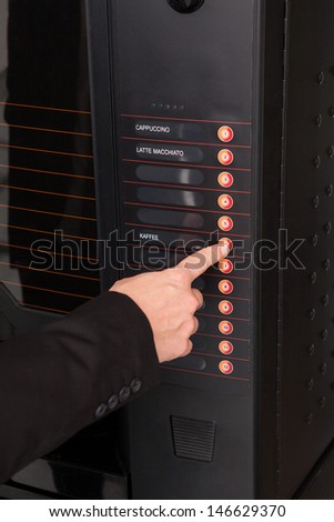 Close-up of hand pressing button of vending machine for coffee