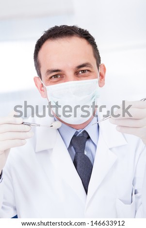 Portrait Of Male Dentist Holding Angled Mirror And Carver