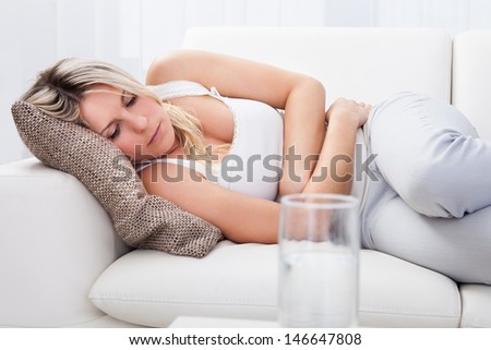Portrait of woman with stomach ache sitting sofa