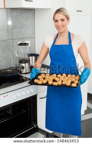 Young Woman With Tray Full Of Cookies From Oven