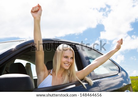 Happy Young Woman Raising Hand Out Of Car Window