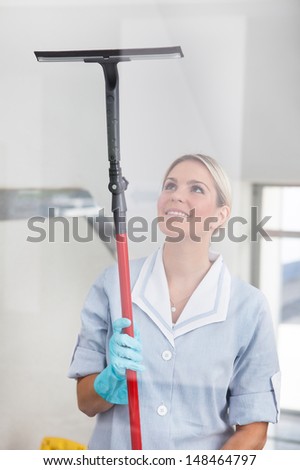 Happy Woman Cleaning Glass With Rubber Window Cleaner