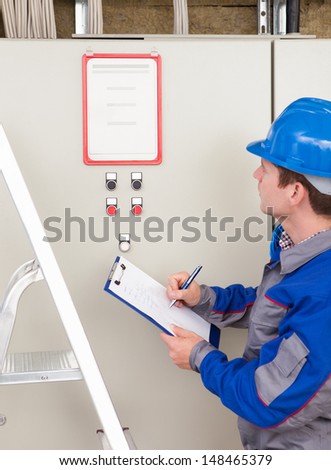 Portrait of young construction worker writing on clipboard