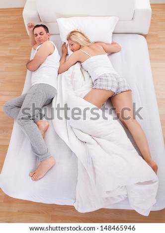 Uncomfortable Husband Sleeping With Wife On Bed
