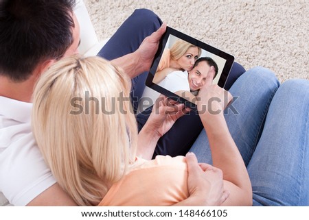 Couple Looking At Picture On Digital Tablet\'s Screen