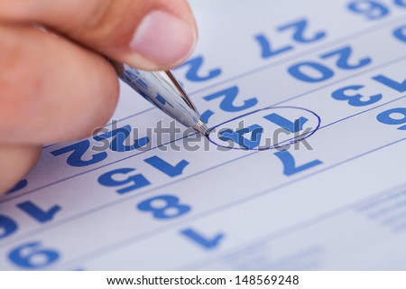 Close-up Of Man Highlighting Date On Calendar