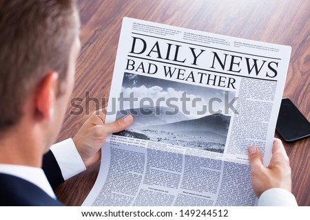 Close-up Of Businessman Reading Weather News On Newspaper