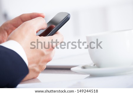 Close-up Of Businessman Using Cell Phone While Having A Break