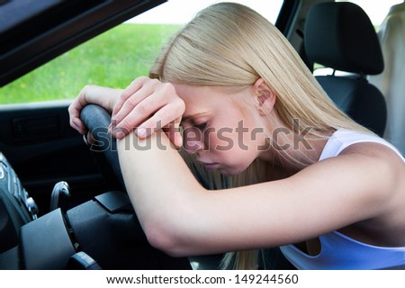 Exhausted Woman Leaning Head On Steering Wheel