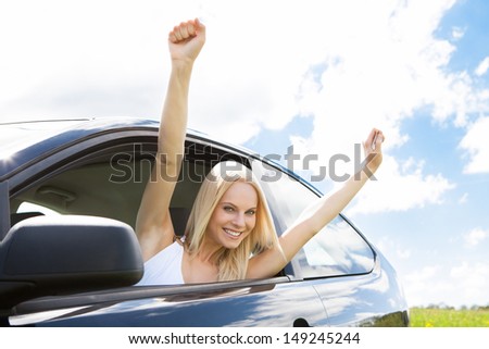 Happy Young Woman Raising Hand Out Of Car Window