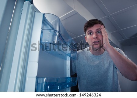 Portrait of a hungry man looking for food in refrigerator