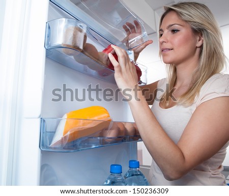 Young Woman Looking For Something In Refrigerator