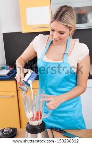 Woman Pouring Milk Into Container For Making Strawberry Milkshake