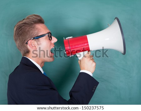 Male Professor Shouting Though Megaphone Against Chalkboard